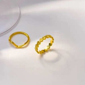 Detailed view of 18K gold plated titanium rings with wavy and star-cut carved textures