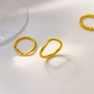 Detailed close-up of wave-shaped 18K gold plated rings with elegant curved engraving