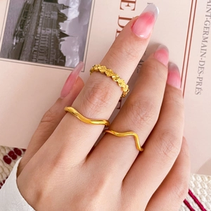 Close-up of stacked wave rings and engraved star pattern ring in 18K gold plated steel