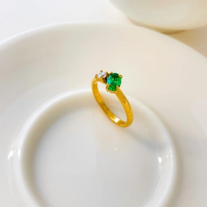 Macro shot of 18K gold plated ring with emerald green zircon and round white crystal