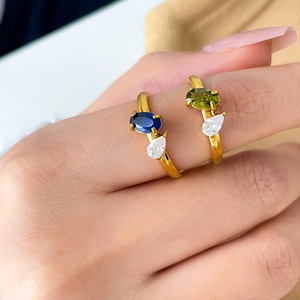 Detail of 18K gold plated rings featuring oval blue and green stones with pear side zircons