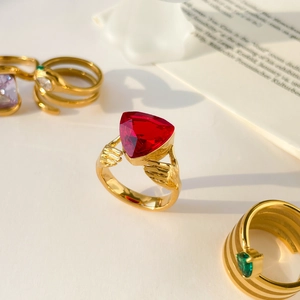 Macro detail of gold snake ring with red heart gemstone and green zircon inlays