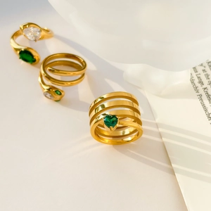 Detailed macro of gold plated snake rings featuring green heart-shaped gemstones