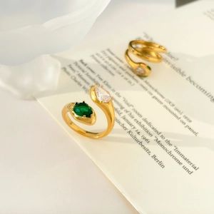 Macro detail of gold-plated wrap rings with emerald-green gems and clear zircon crystals