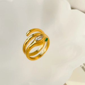 Macro detail of gold snake ring featuring green zircon eyes and white marquise stone
