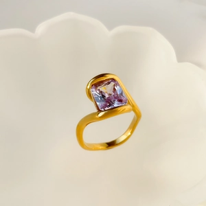 Macro shot of gold plated snake-style ring featuring a square-cut lavender gemstone