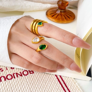 Close-up of three gold-plated rings set with pear-cut green and clear zircon stones