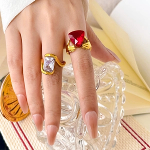 Detail of 18K gold plated snake-style rings with large purple and red gemstones on a hand