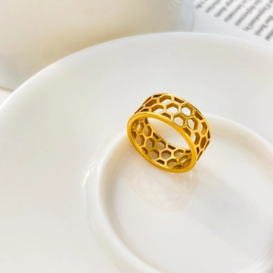 Detail shot of a wide gold honeycomb hollow pattern ring in polished stainless steel