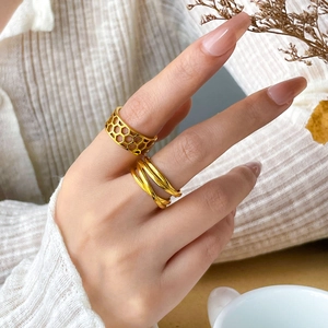 Detail of gold hollow hexagonal and multi-layered rings worn in an elegant lifestyle setting