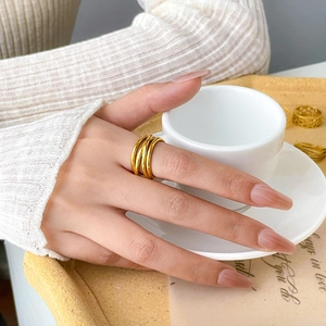 Detail of layered gold spiral wide ring worn on finger with minimalist hollow lines