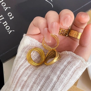 Detail shot of multilayer gold rings with hammered texture and hollow design on a hand