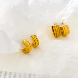 Macro shot of gold-plated pumpkin pattern earrings with triple-line grooves and polished texture