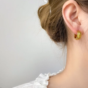Detail of gold titanium steel hoop earrings with three vertical ribbed pumpkin stripes