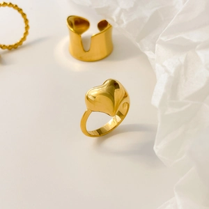 Detailed view of polished golden heart ring and wide concave open band with metal beads