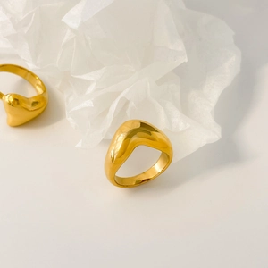 Macro view of two polished gold irregular wave rings on a white textured background
