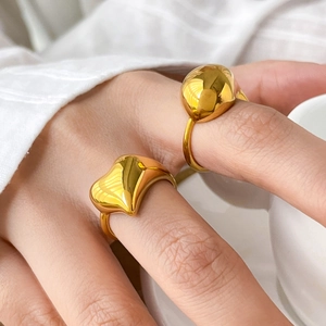 Polished gold organic heart and spherical open ring set shown on a model's hand