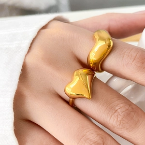 Macro shot of gold-plated heart and curved organic rings with premium mirror polish