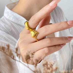 Close-up of a minimalist gold heart-shaped ring with a polished wide band finish