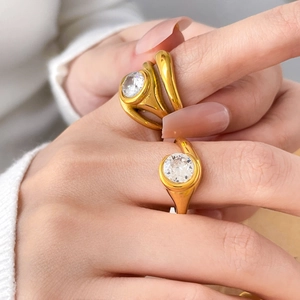 Dettaglio di anelli placcati in oro 18K con zircone rotondo e design ondulato minimalista