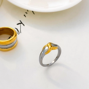 Macro detail of two-tone gold and silver knot ring with polished stainless steel finish