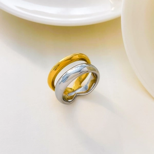 Detail of interlocking gold and silver stainless steel rings on a white porcelain background