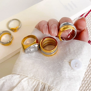 Detailed view of layered mixed-tone gold and silver rings with an embossed portrait signet