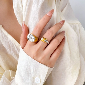 Close-up of bicolor face relief ring and layered metal band on model fingers