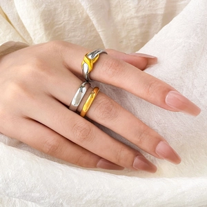 Detail of layered gold and silver mixed metal rings with hollow X design on fabric