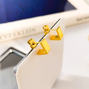 Detalle macro de pendientes geométricos en forma de L chapados en oro 18K pulido