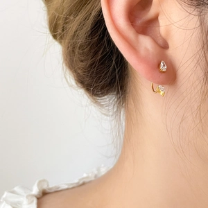 Elegantes pendientes dorados con doble gota de circón lucidos por una modelo con estilo