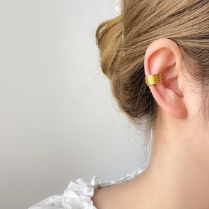 Detalle de un elegante ear cuff dorado de capas múltiples para cartílago sin agujero