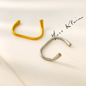 Detail of minimalist gold and silver two-tone curved open bangles with high-gloss finish