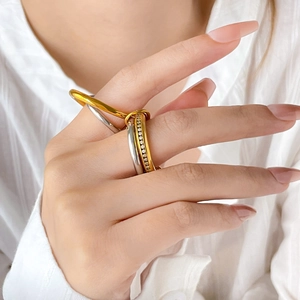 Interlocked tri-color titanium steel rings with pavé crystals on a model's hand