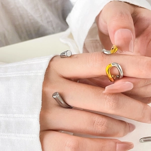 Detail of stacked two-tone stainless steel open rings with curved and twisted metal design