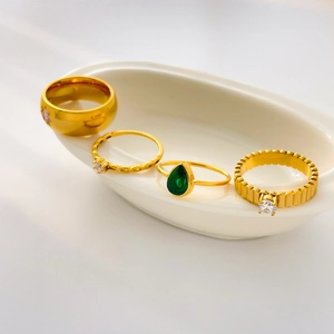 Set of four gold titanium rings with green pear-shaped zircon and minimalist textures
