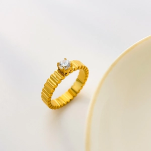 Detailed view of a gold-plated ribbed ring featuring a brilliant round cubic zirconia stone