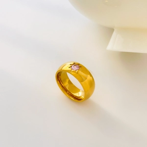 Macro detail of gold-plated titanium steel ring with pink zircon and starburst engraving