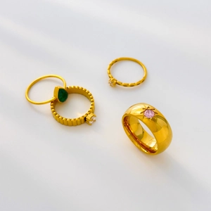 Detailed set of four gold titanium steel rings with green, pink, and clear zircons