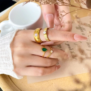 Detailed stack of gold titanium rings featuring green drop and pink star zircons