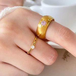 Detail of gold rings featuring a star-set pink zircon and a delicate wave band with white stone