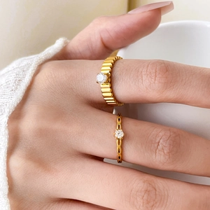 Close-up of gold titanium steel rings with cubic zirconia on a hand by a cup