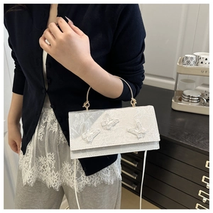 Detailed view of white floral lace handbag with 3D butterfly appliques and gold handle