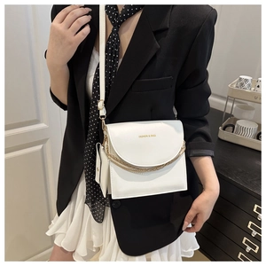 Detail of white leather crossbody bag with double gold chains and mini coin purse charm
