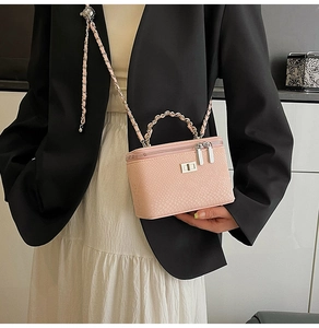Pink snake skin crossbody bag with gold chain strap and metal handle on model