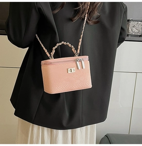 Detail of light pink snake skin textured box bag with gold metal chain strap and top handle