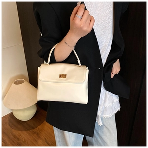 Detail of cream soft leather handbag with gold twist lock on a vintage background
