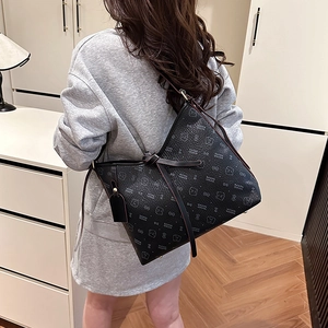 Black leather tote bag with cute bear patterns and top bow detail worn by a model
