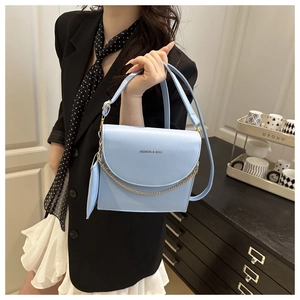 Detail of light blue faux leather square bag with gold chain and engraved fashion text