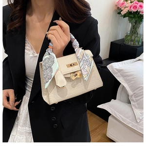 Detail of off-white faux crocodile leather kelly bag with floral scarf on handle